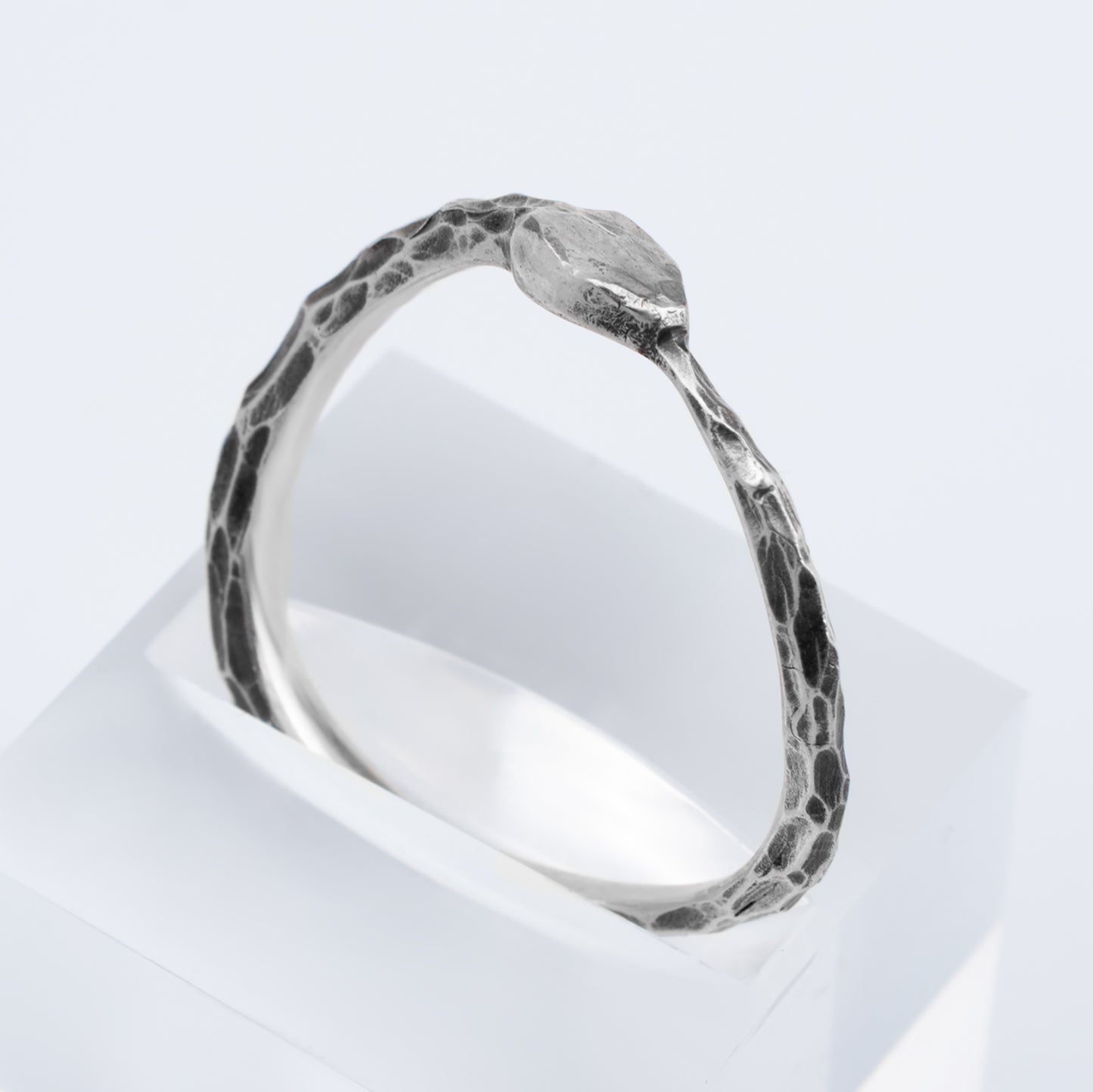 Silver ring with a textured band on a white background