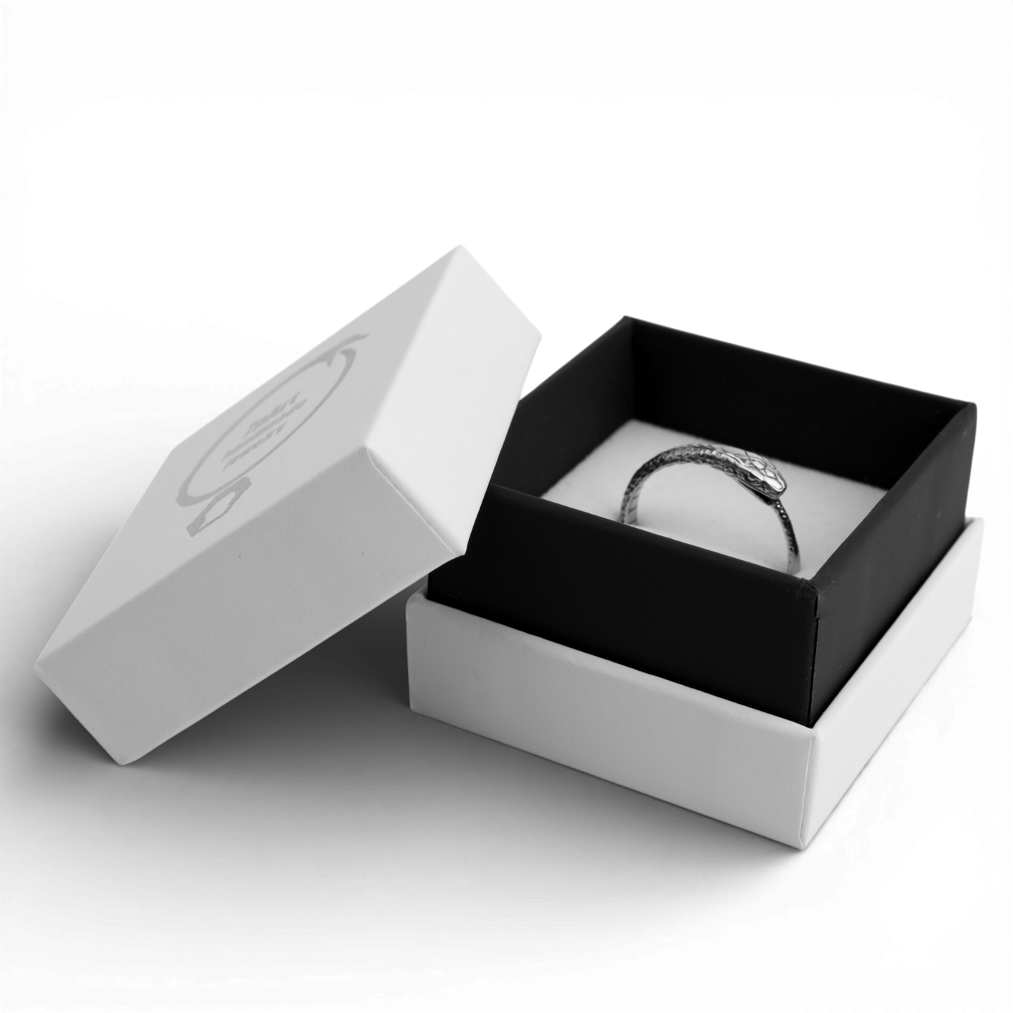 Silver ring in a black and white jewelry box on a white background