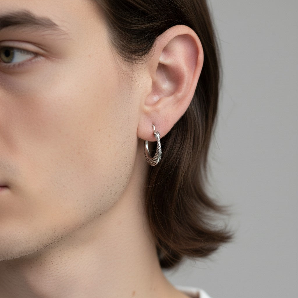 Close-up of a person wearing a silver hoop earring against a neutral background